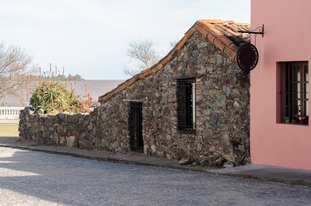 Historic stone building with a clock mounted on its exterior wall in Colonia del Sacramento
