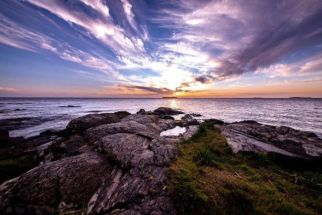 Dramatic sunset over the Río de la Plata with a rocky shoreline and sweeping clouds in Colonia del Sacramento