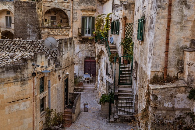 Narrow stone alleyway lined with historic limestone homes, staircases, and balconies in Matera's Sassi district