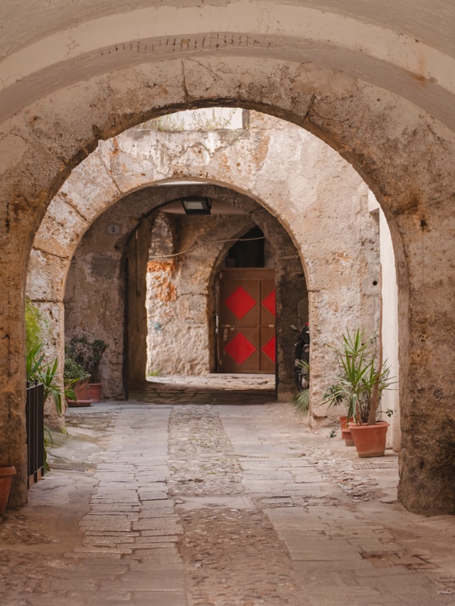 Historic stone passageway framed by multiple arches leading through a quiet courtyard in Matera