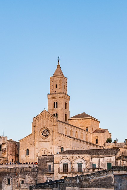 Large historic church with a tall bell tower rising above the stone buildings of Matera