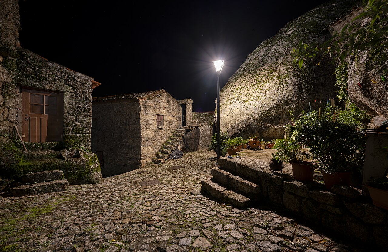 Cobblestone street in Monsanto Portugal at night beside a giant granite boulder