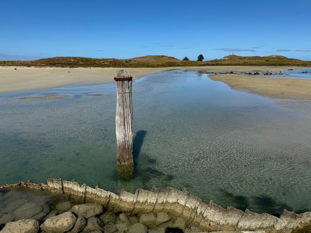 Tranquil coastal landscape at Port Fairy with a wooden post rising from clear calm waters