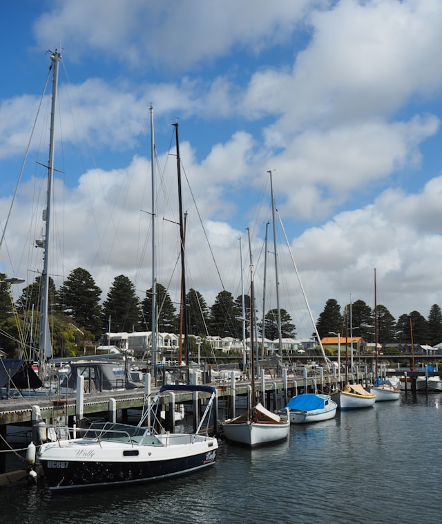 Sailboats docked in the Port Fairy marina with trees and buildings in the background