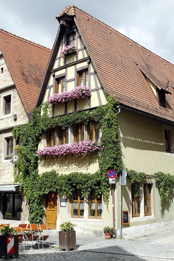 Ivy-covered half-timbered house with pink geraniums, the Landsknechtstube, in Rothenburg ob der Tauber