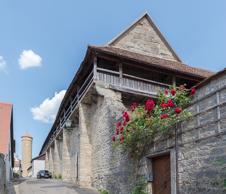 Section of the medieval town wall of Rothenburg with its covered wooden walkway and climbing red roses