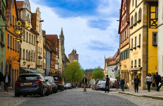Cobblestone street in Rothenburg ob der Tauber leading toward a medieval tower and church spire