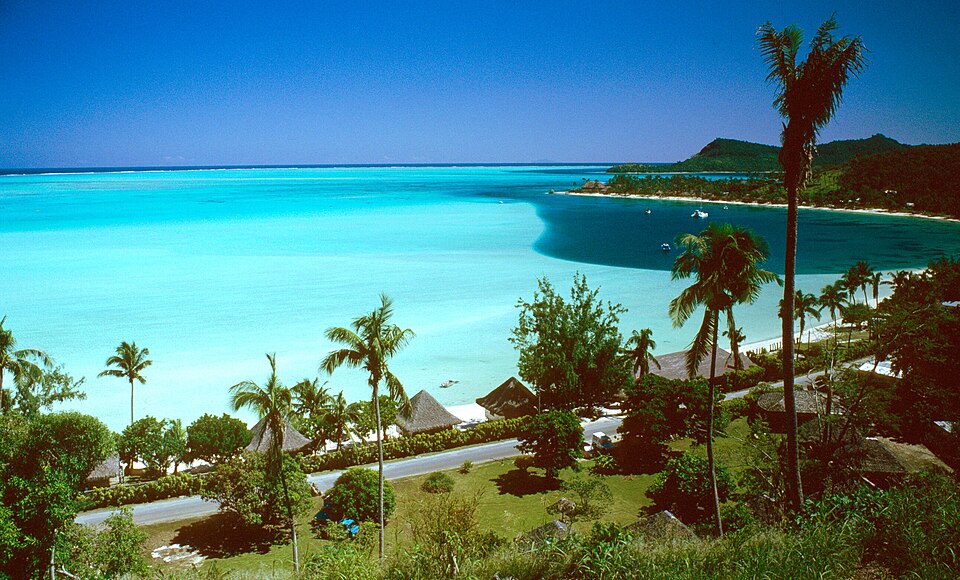A hillside view looking down over Matira Beach's turquoise lagoon and coastal road in Bora Bora French Polynesia