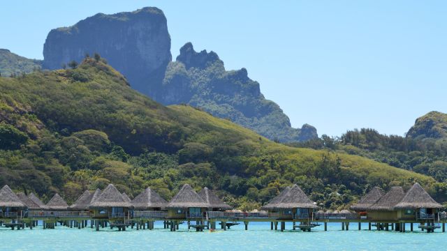 A long row of thatched overwater bungalows stretching across a lagoon