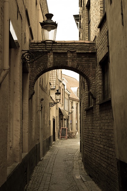 Narrow alley with a stone arch and hanging lantern in Bruges Belgium