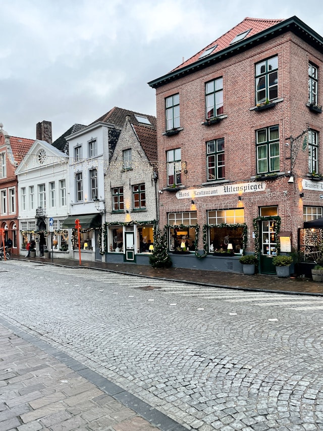 Cobblestone street lined with shops including Hotel Restaurant Uilenspiegel in Bruges Belgium