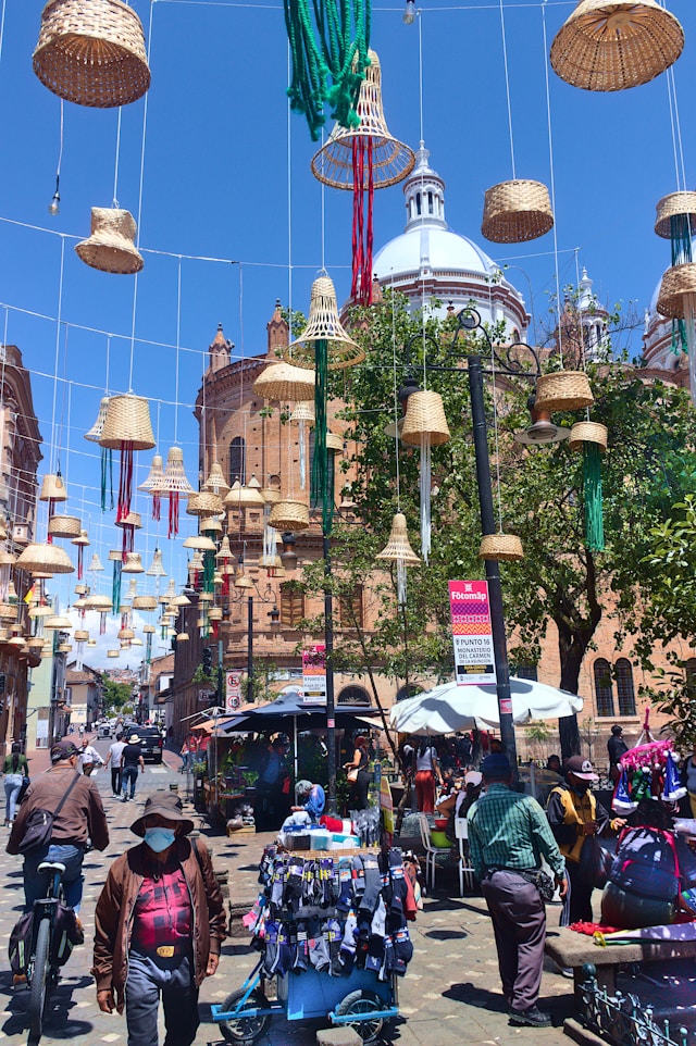 Woven basket lampshades strung above a plaza with cathedral domes in view