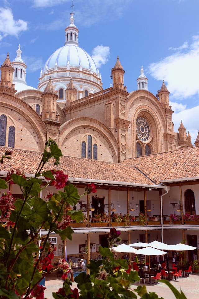 Blue and white tiled cathedral domes rising above a flower filled courtyard restaurant in Cuenca Ecuador