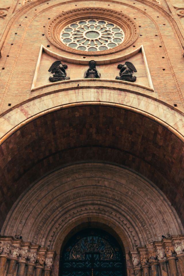 A close up of the cathedral's carved stone entrance beneath a rose window in Cuenca Ecuador