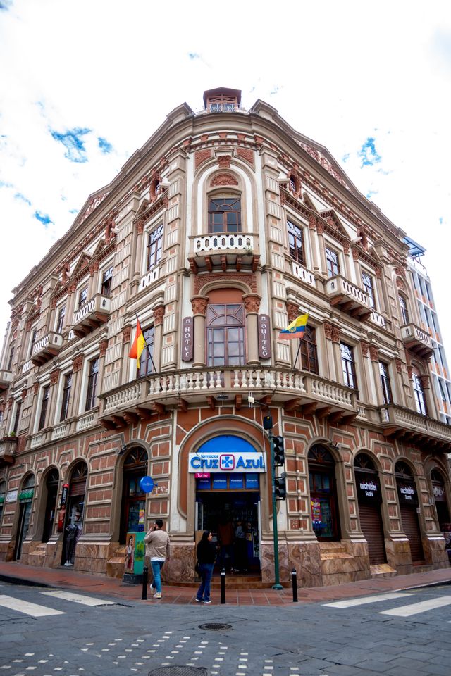 An ornate corner building with carved stone balconies and ground floor shops