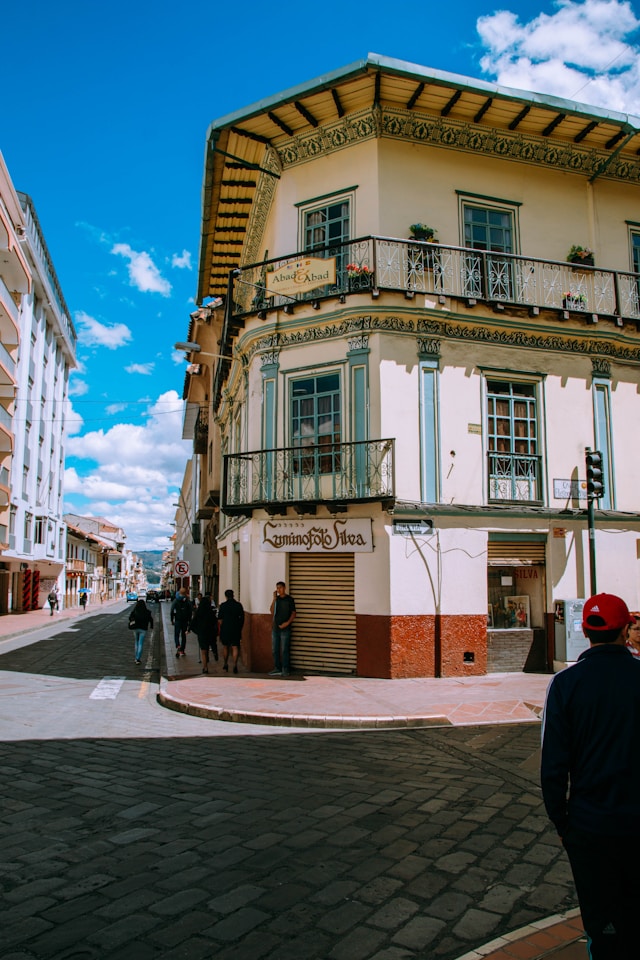A cream colored corner building with wrought iron balconies on a cobblestone street corner
