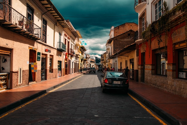 A parked car on a cobblestone street beneath a dramatic teal evening sky