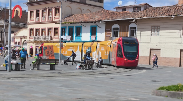 A red and yellow streetcar curving through a historic plaza