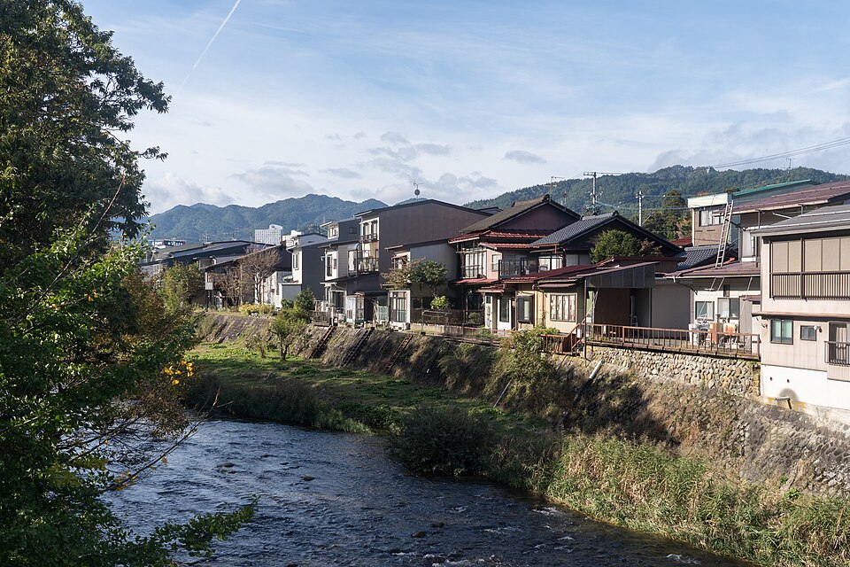 Miya River lined with houses and mountains in the background