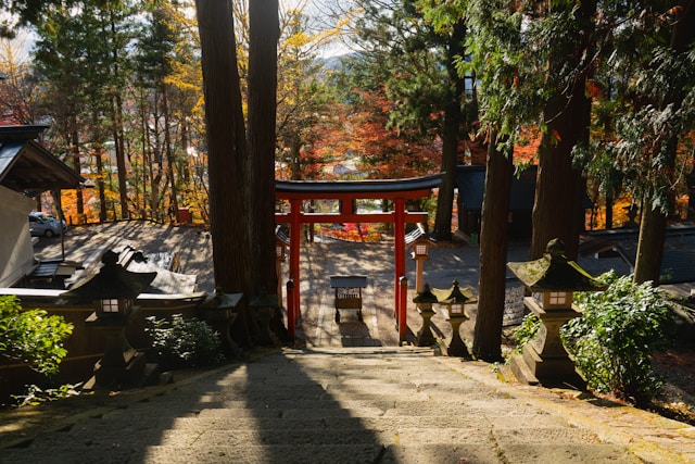 Red torii gate framed by autumn foliage at a Takayama shrine