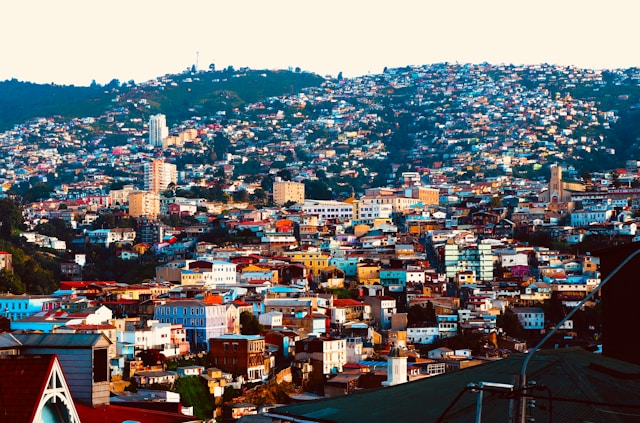 Aerial view of a dense hillside neighborhood with a church tower and high-rise apartments in Valparaiso Chile