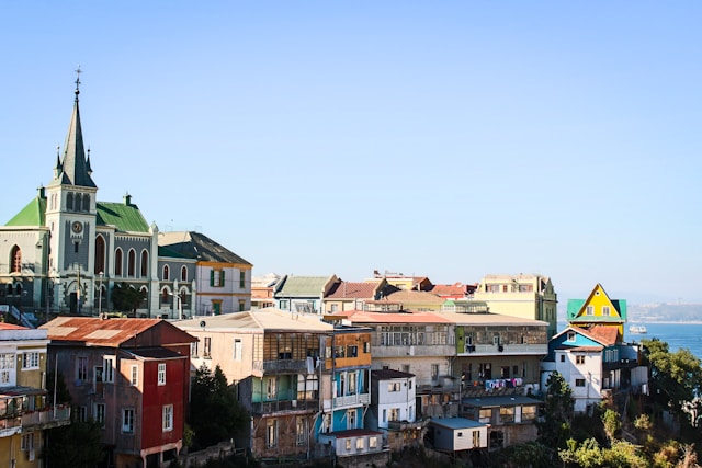 A Gothic-style church tower rising above a row of colorful hillside homes in Valparaiso Chile