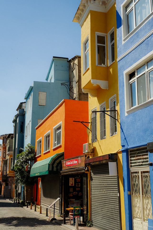 A row of narrow buildings painted in mismatched blue, yellow, and orange facades in Valparaiso Chile