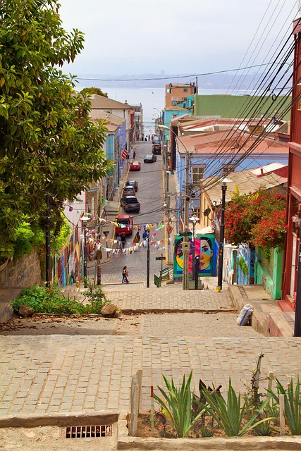 A steep cobblestone street lined with bunting and a large mural of a woman's face