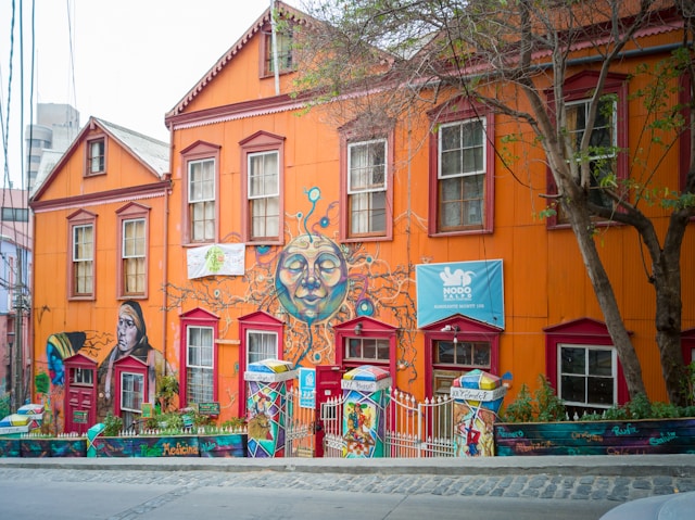 A bright orange building with a large mural of a face painted across its facade
