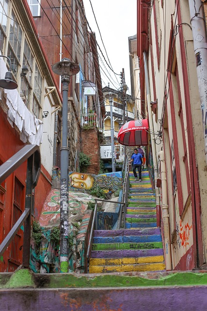 A narrow alley stairway painted in rainbow stripes between graffiti-covered walls