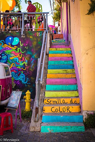 Stairs painted pink, teal, and yellow beside the words Semilla de Color
