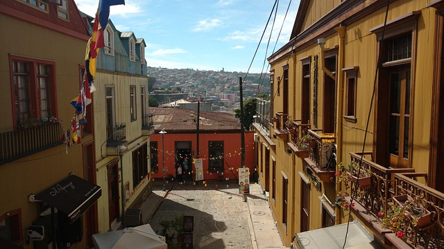 A narrow hillside street strung with flags between yellow buildings