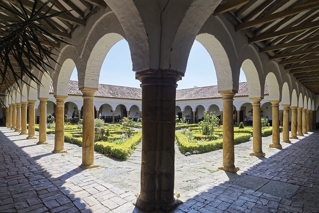 Stone cloister with arched columns surrounding a manicured garden