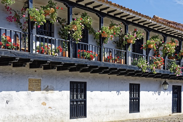 Wooden balcony overflowing with red and pink potted flowers in Villa de Leyva Colombia