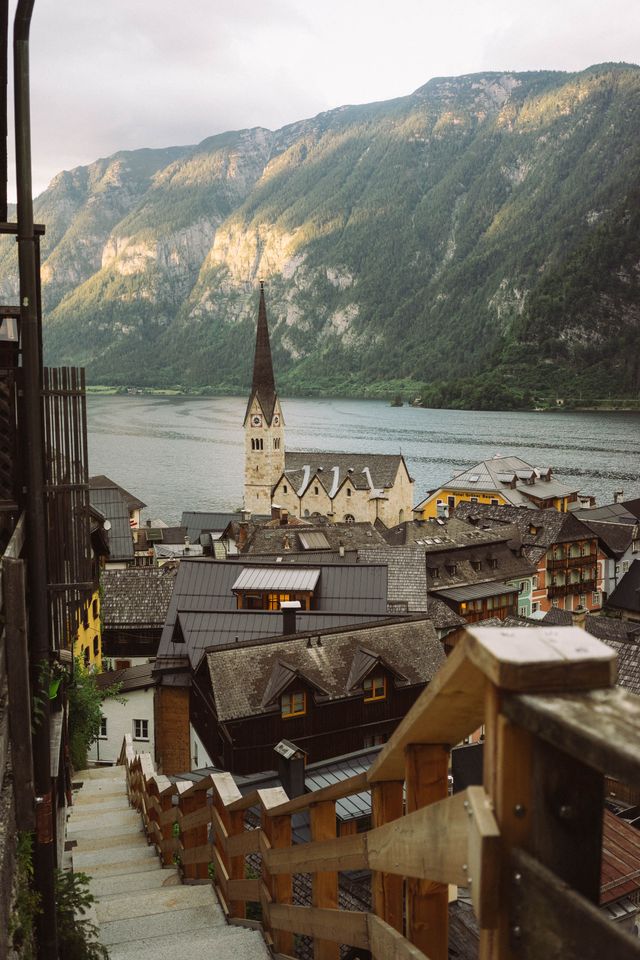 View down a wooden staircase toward Hallstatt's church spire and lake