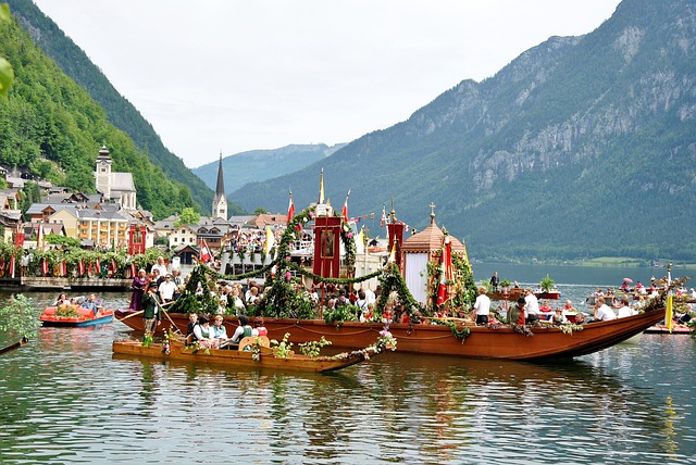 Traditional decorated boats carrying a lake procession past Hallstatt's church