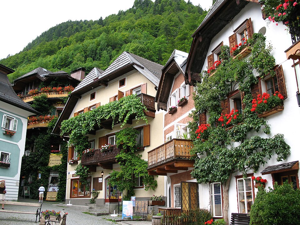 Orange, white, and green houses with stacked firewood in Hallstatt's market square