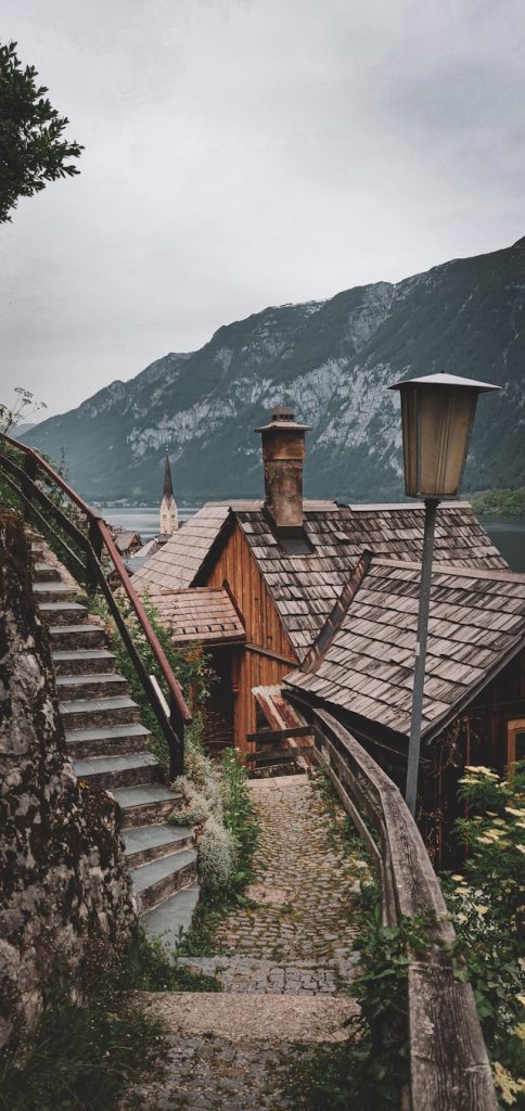 Stone steps descending past wooden lakeside houses toward Hallstatt's church spire