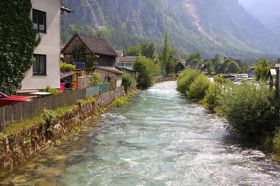 A clear mountain stream flowing through Hallstatt past houses and mountains