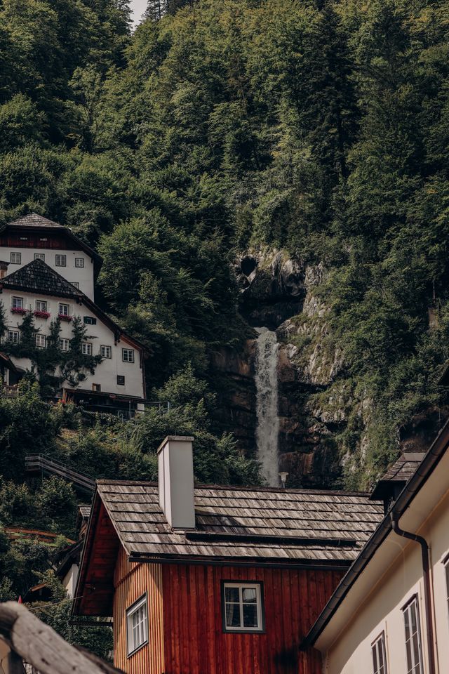 A waterfall cascading down the cliffs behind Hallstatt's village houses