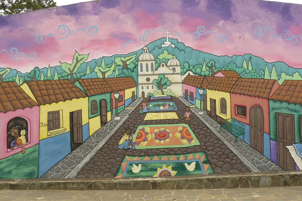 Mural of a colorful village street on a wall in Ataco