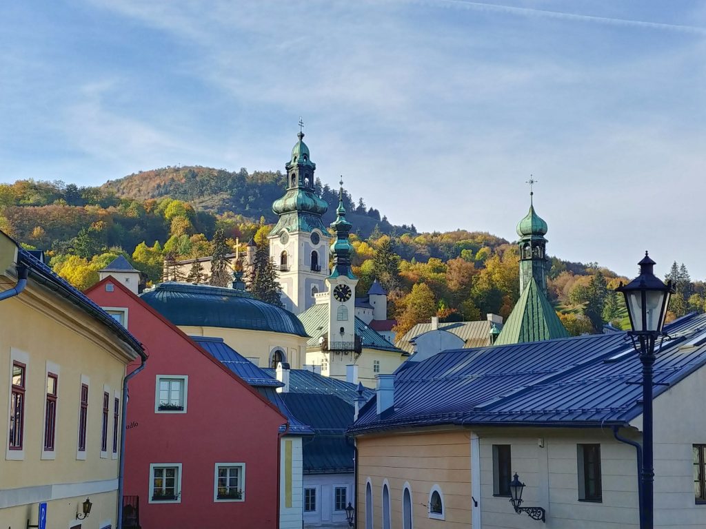 Colorful houses and church towers beneath a wooded hill in Banská Štiavnica