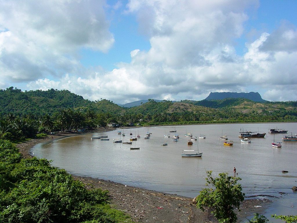 Fishing boats anchored in a calm bay surrounded by green hills