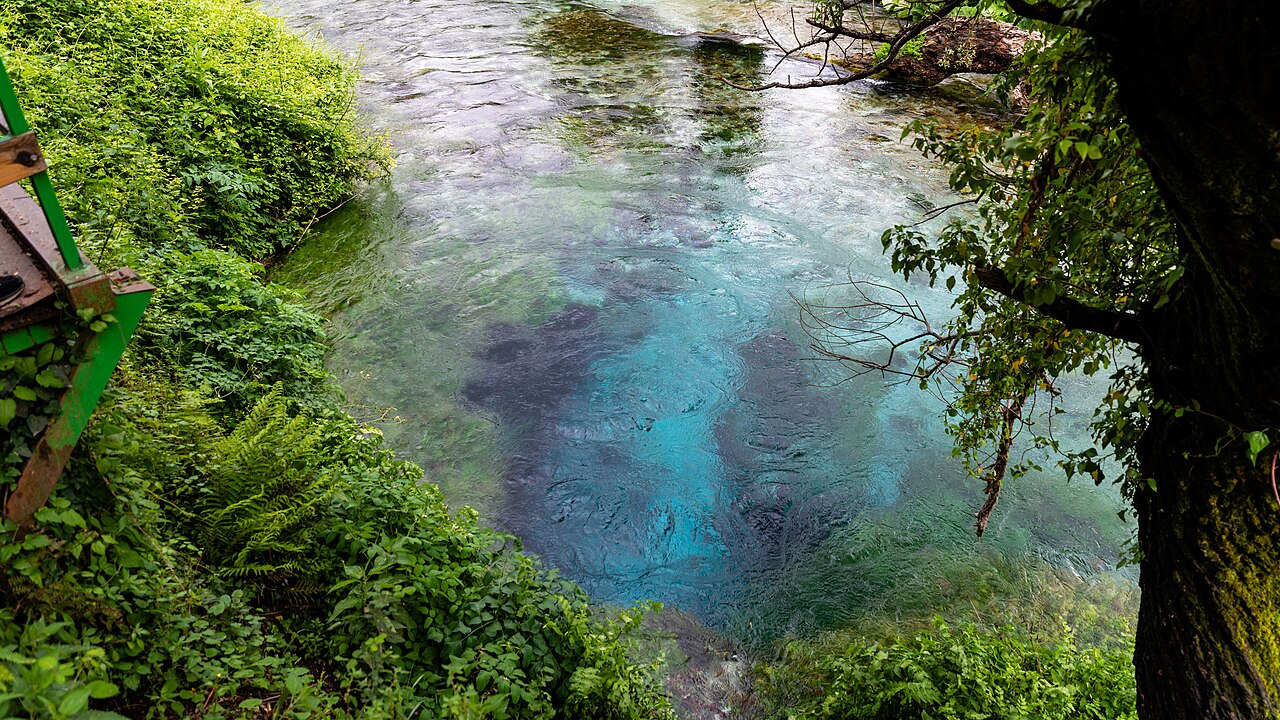 Deep blue spring water surrounded by green trees at the Blue Eye