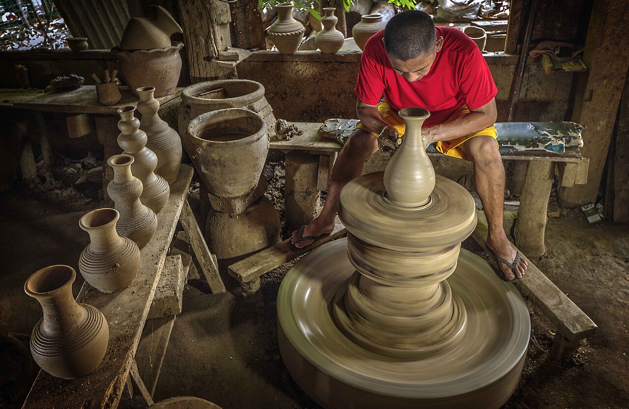 Potter shaping a clay burnay jar at a traditional workshop