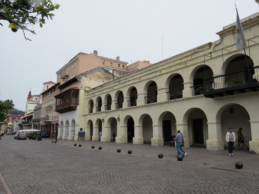 A colonial building with white arches beside the plaza