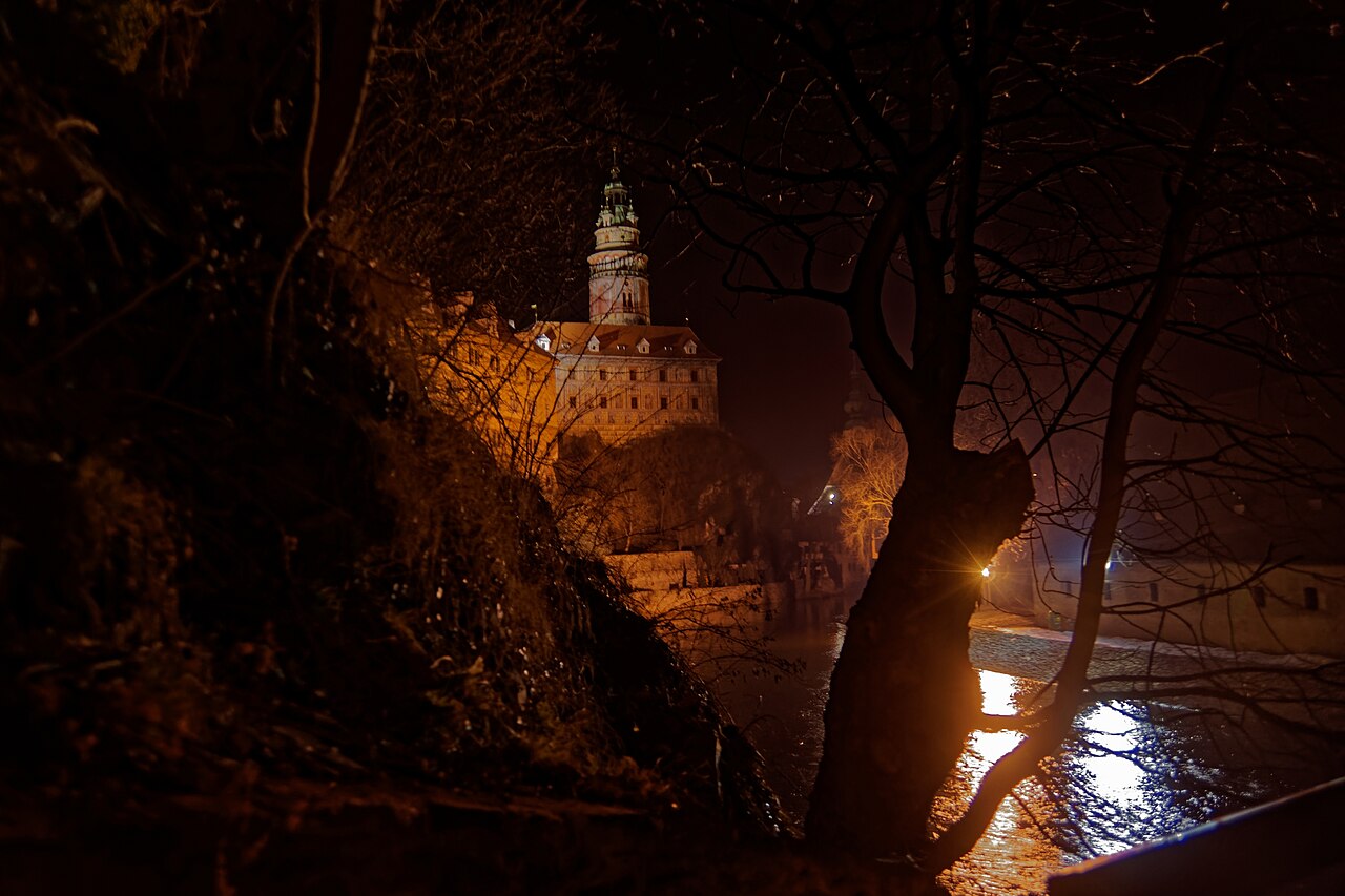 Illuminated castle tower of Český Krumlov seen from Rybářská street at dusk