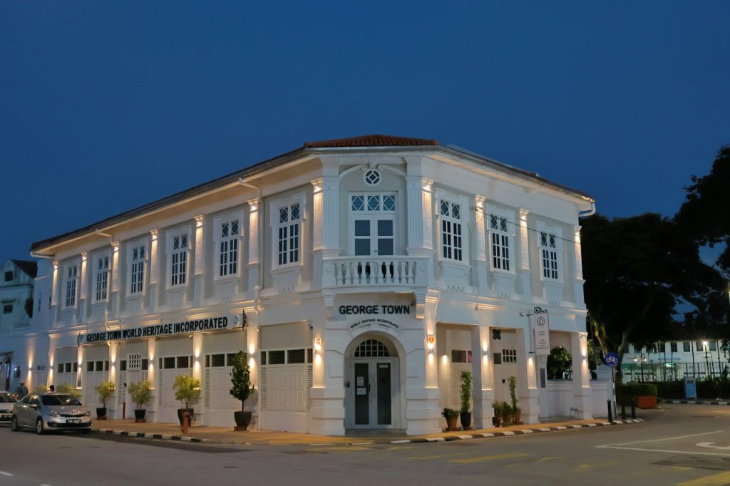 A white colonial building lit up at dusk