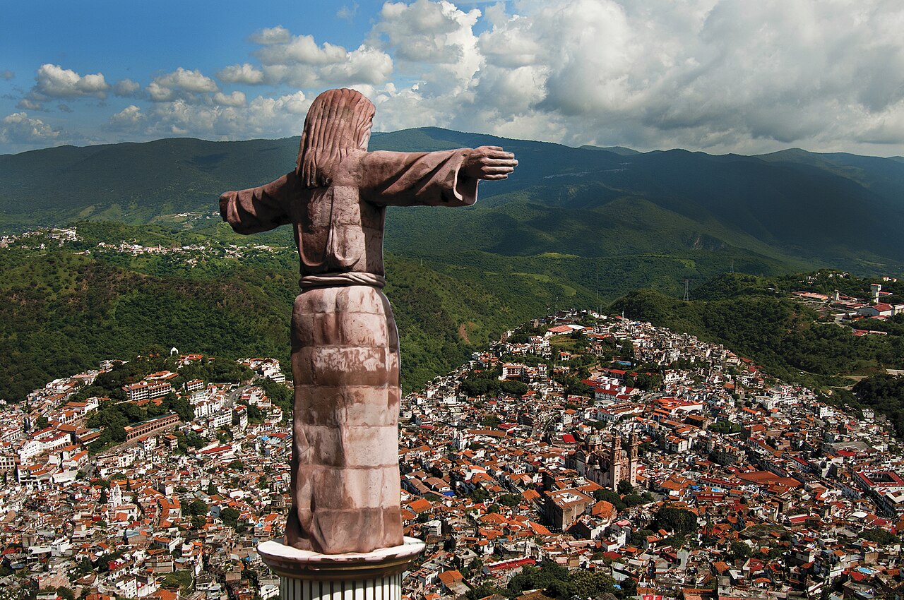Large white statue of Christ above a town
