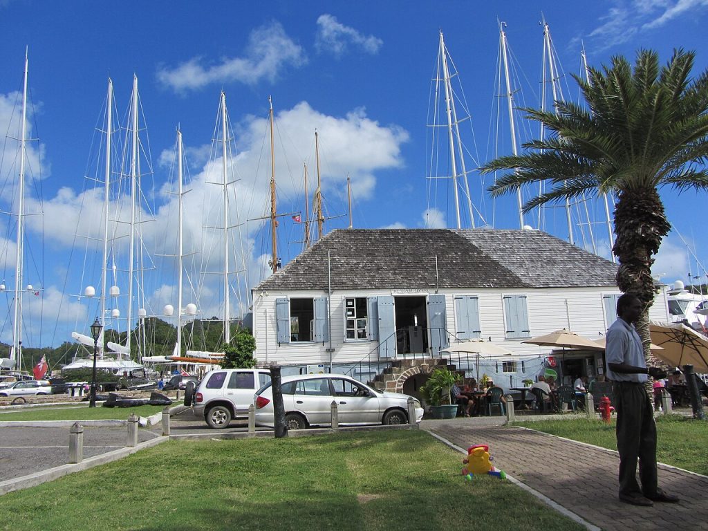 A white historic building with masts of yachts behind